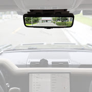 Car interior with a rearview mirror displaying a road scene.