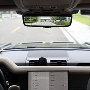 Car interior with a mounted rearview mirror displaying a wide-angle view of the road.